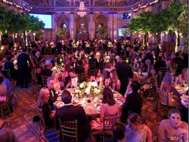 Spring Ball seated at tables, surrounded by greenery and warm lighting.