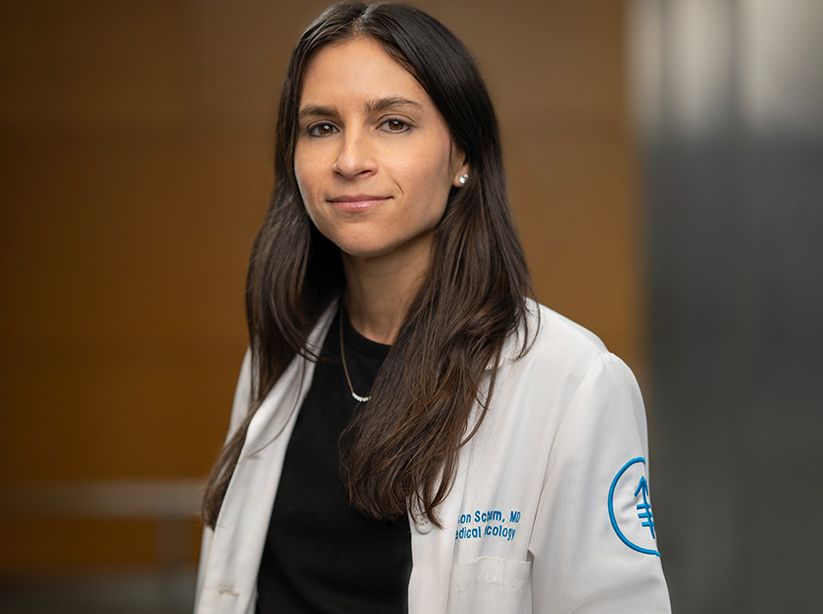Dr. Alison Schram, a gynecologic medical oncologist and early drug development specialist, wearing a white lab coat in an indoor setting. 