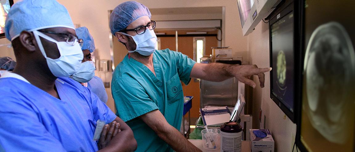 Three MSK researchers look at an image on a screen.