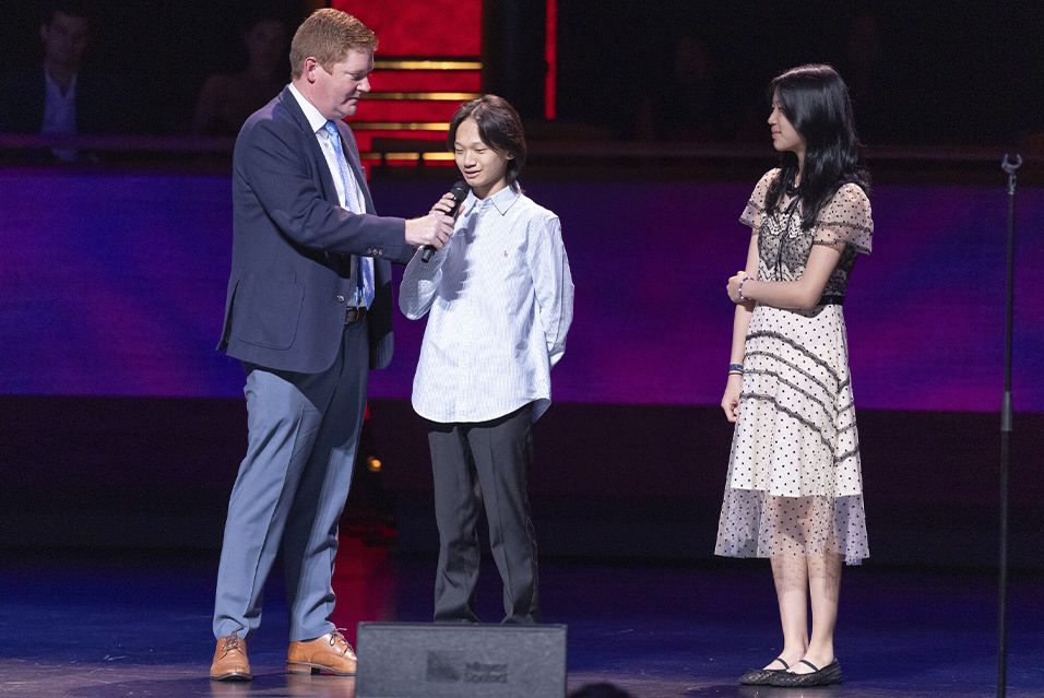 MSK’s Dr. Kevin Curran on stage at Comedy vs Cancer with his young patient, Eric, and Eric’s sister, Anna.