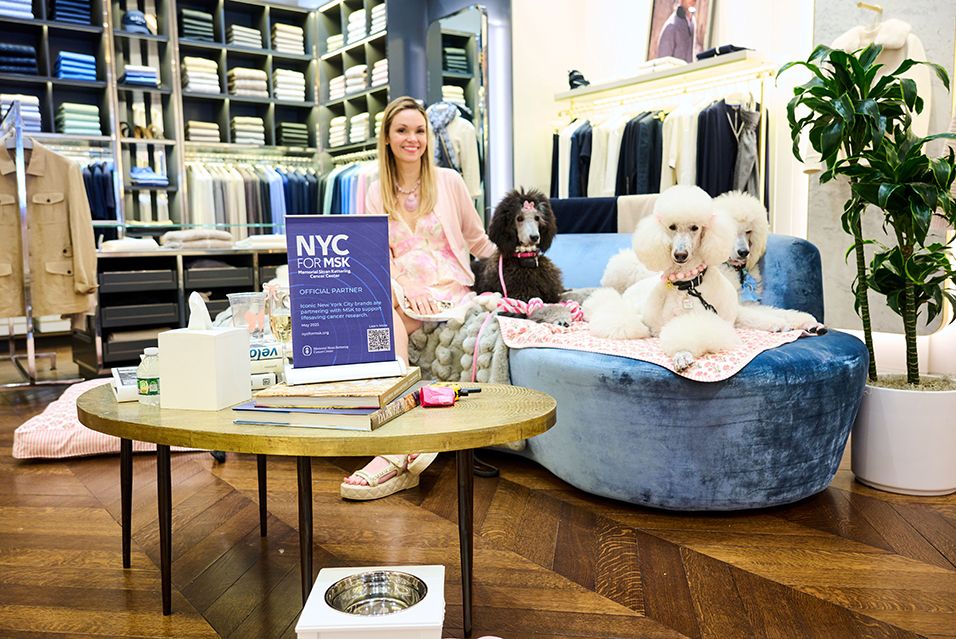 A woman and three poodles seated on a couch inside the N.Peal store on Madison Avenue in New York City during NYC for MSK.  