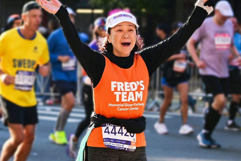 A Fred’s Team runner smiling with arms raised while participating in the TCS New York City Marathon.  