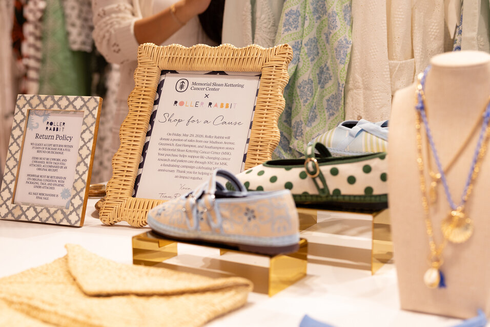 A table of Roller Rabbit merchandise and a sign with information about the shopping event benefiting MSK.