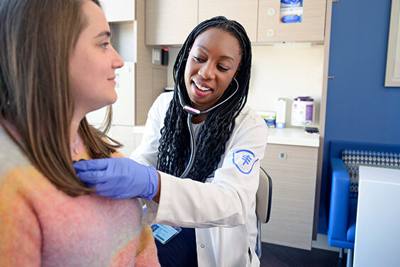 Doctor smiling while examining a patient with a stethoscope.